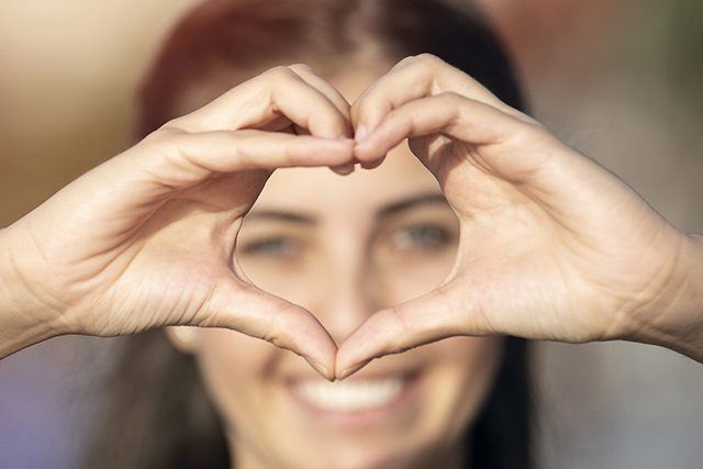 A woman making a heart shape with her hands around her eyes
