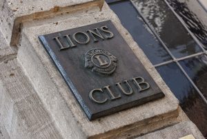 A sign that says "Lion's Club" on the side of a stone building
